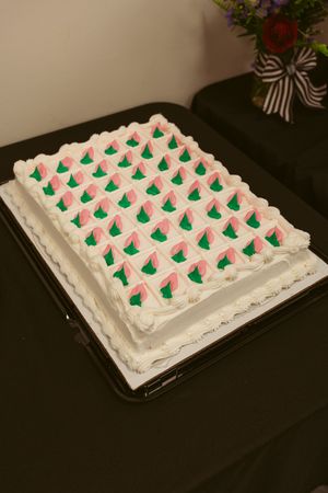 A rectangular white frosted cake decorated with a uniform pattern of small green Christmas trees piped in frosting.