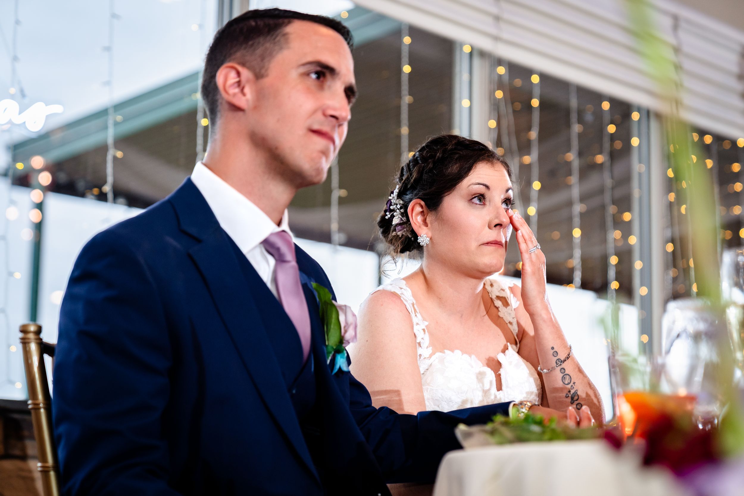 Guests seated at decorated tables during wedding reception speeches.