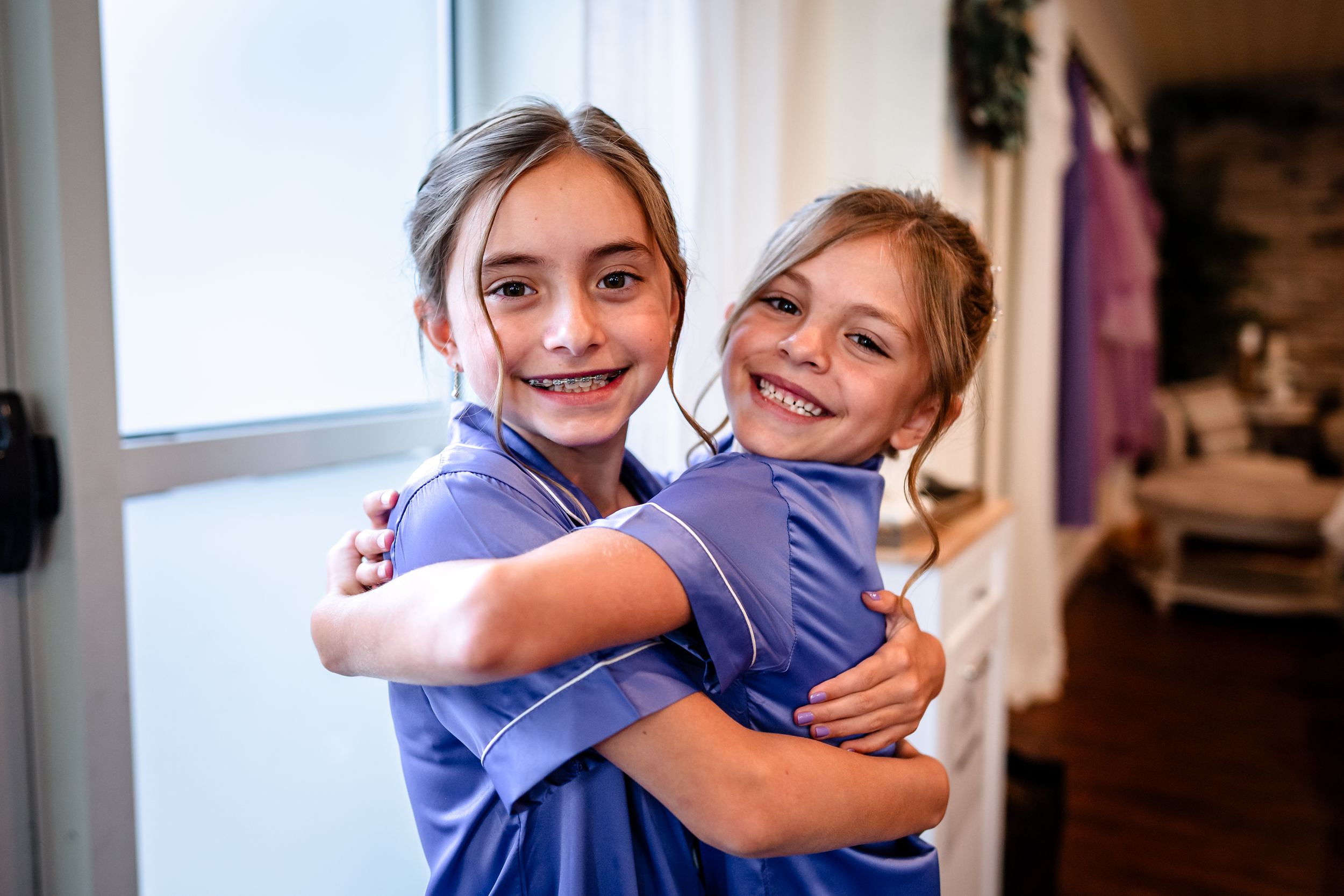 Joyful embraces and candid moments shared between friends in matching blue robes during pre-wedding preparations.