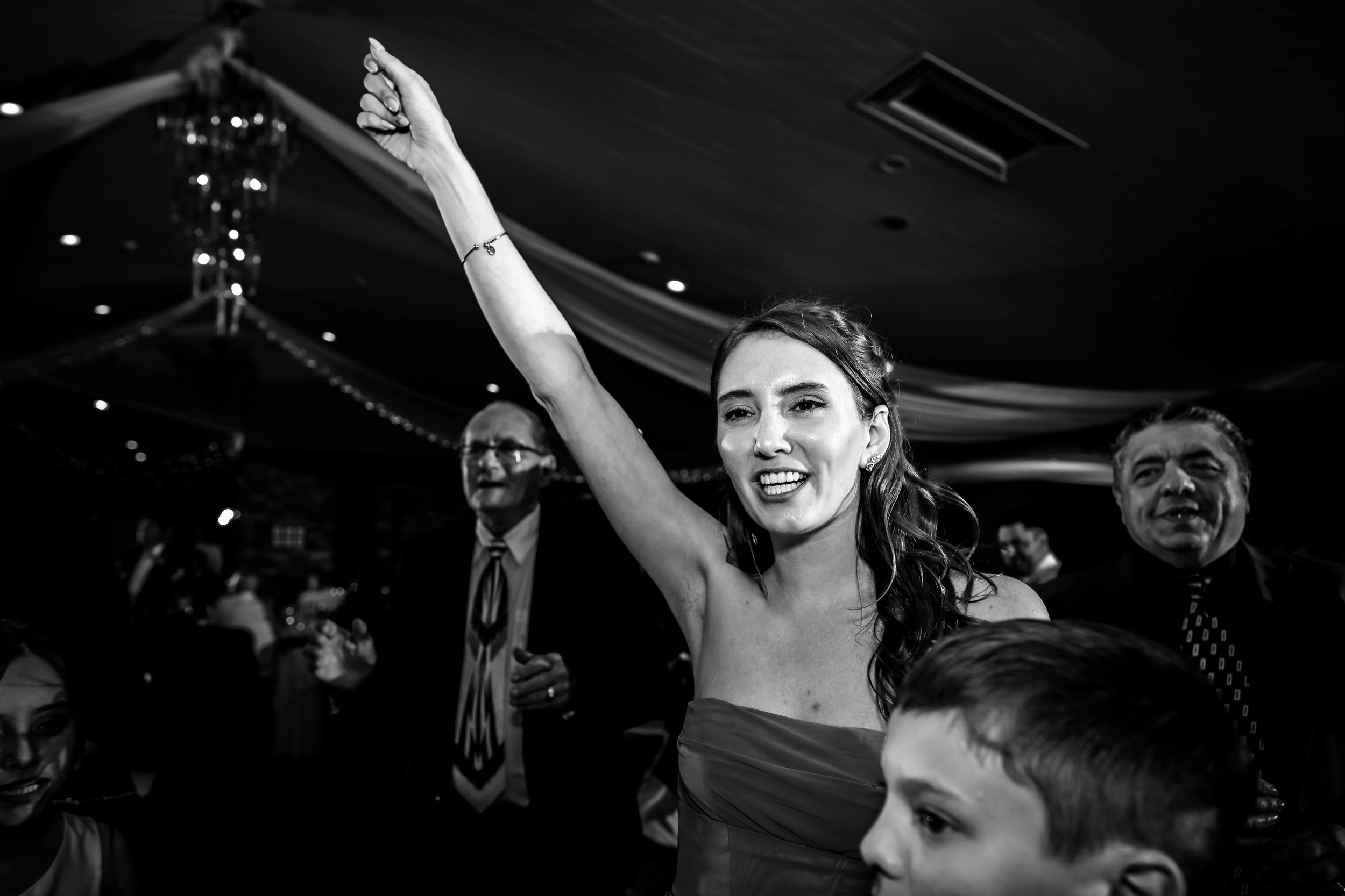 Wedding guests dancing and celebrating on a dimly lit dance floor.