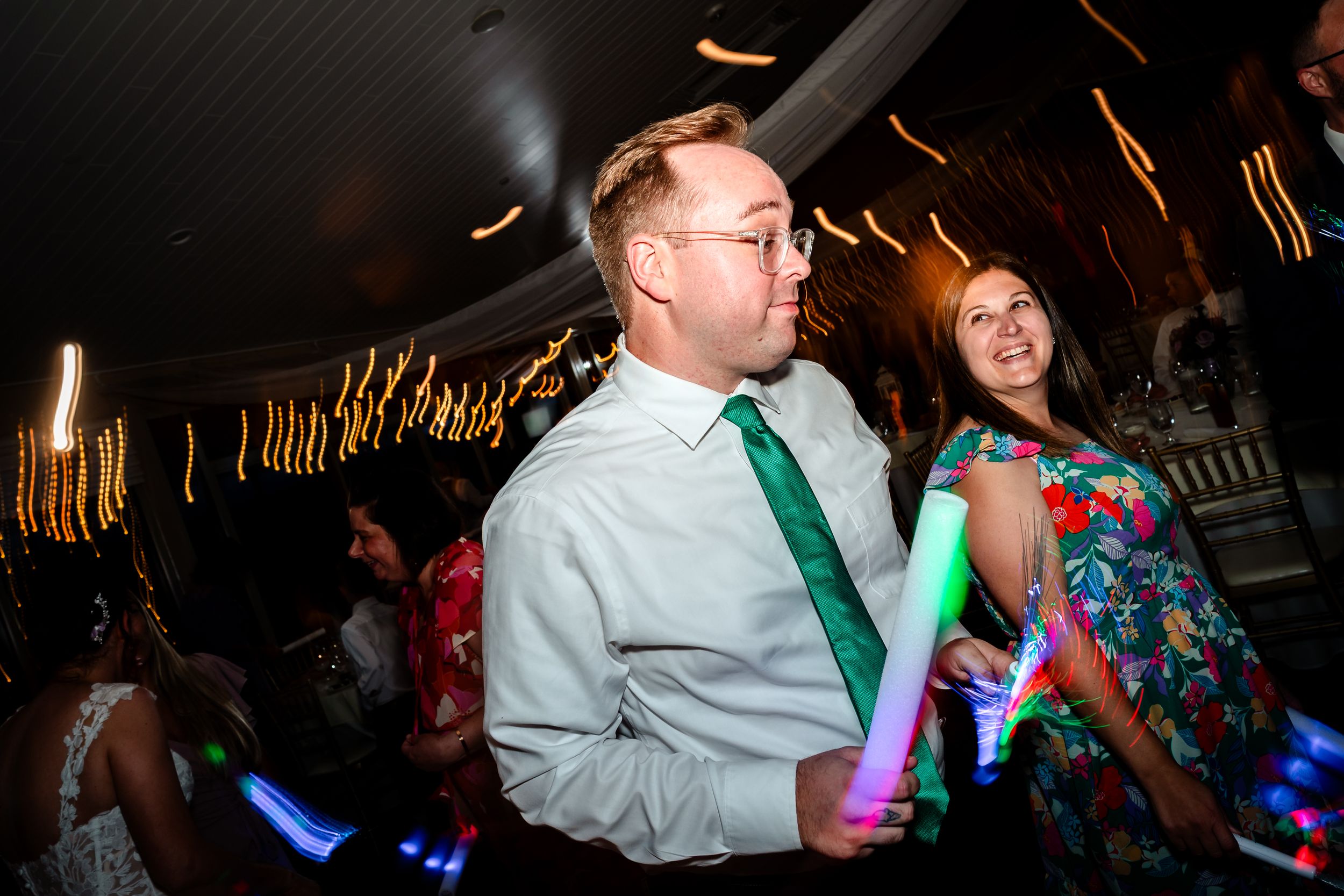 Energetic dance party with colorful LED light sticks creating streaks of motion in the dark.