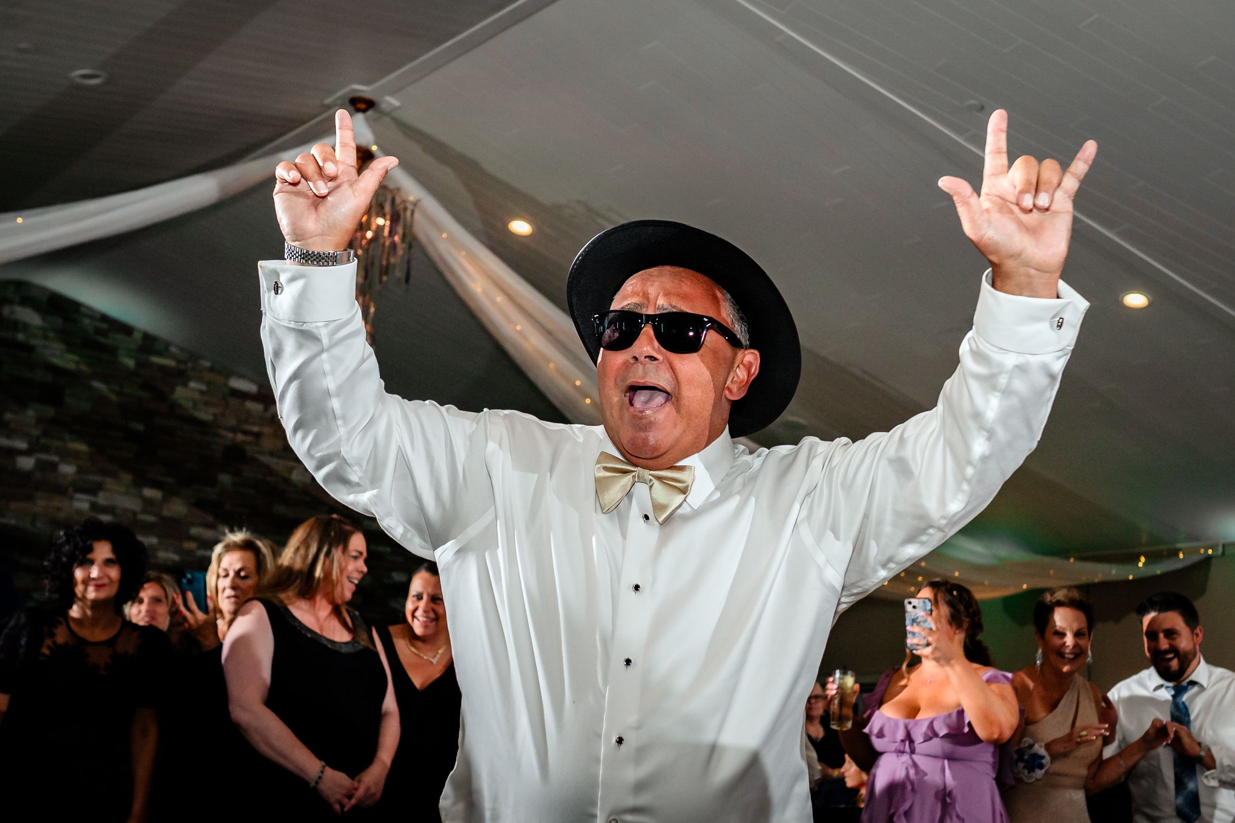 Wedding guests dancing enthusiastically on the dance floor with raised arms.