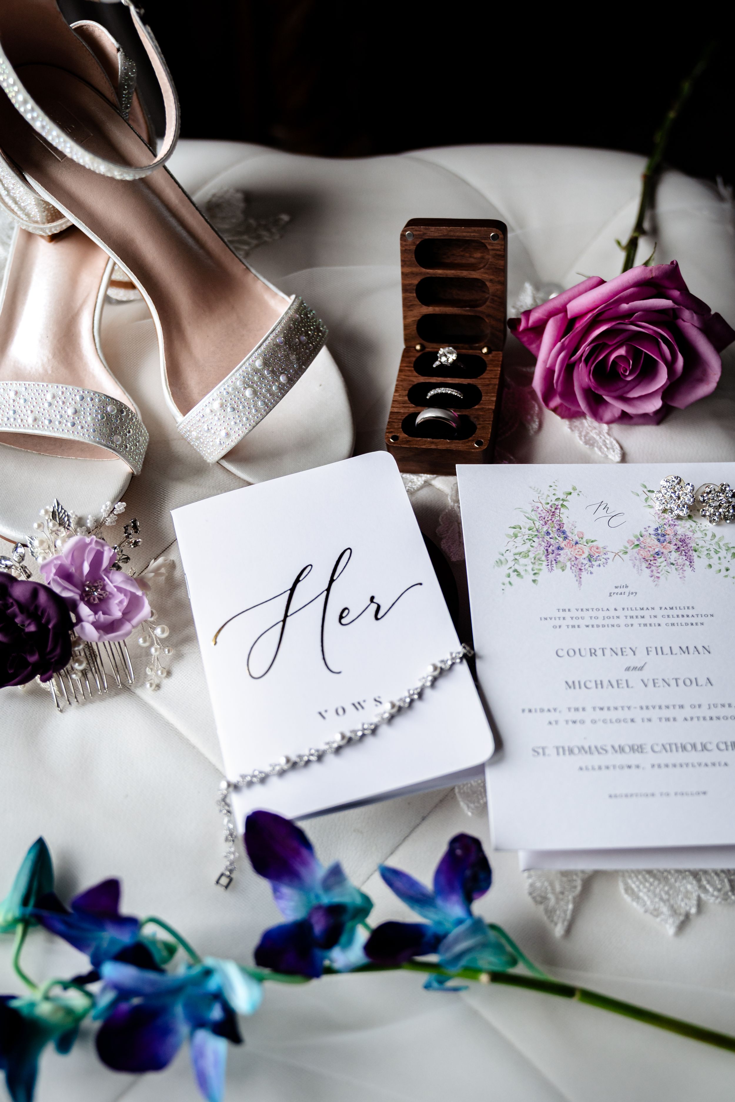 Elegant wedding stationery with floral details alongside blue orchids and bridal accessories.
