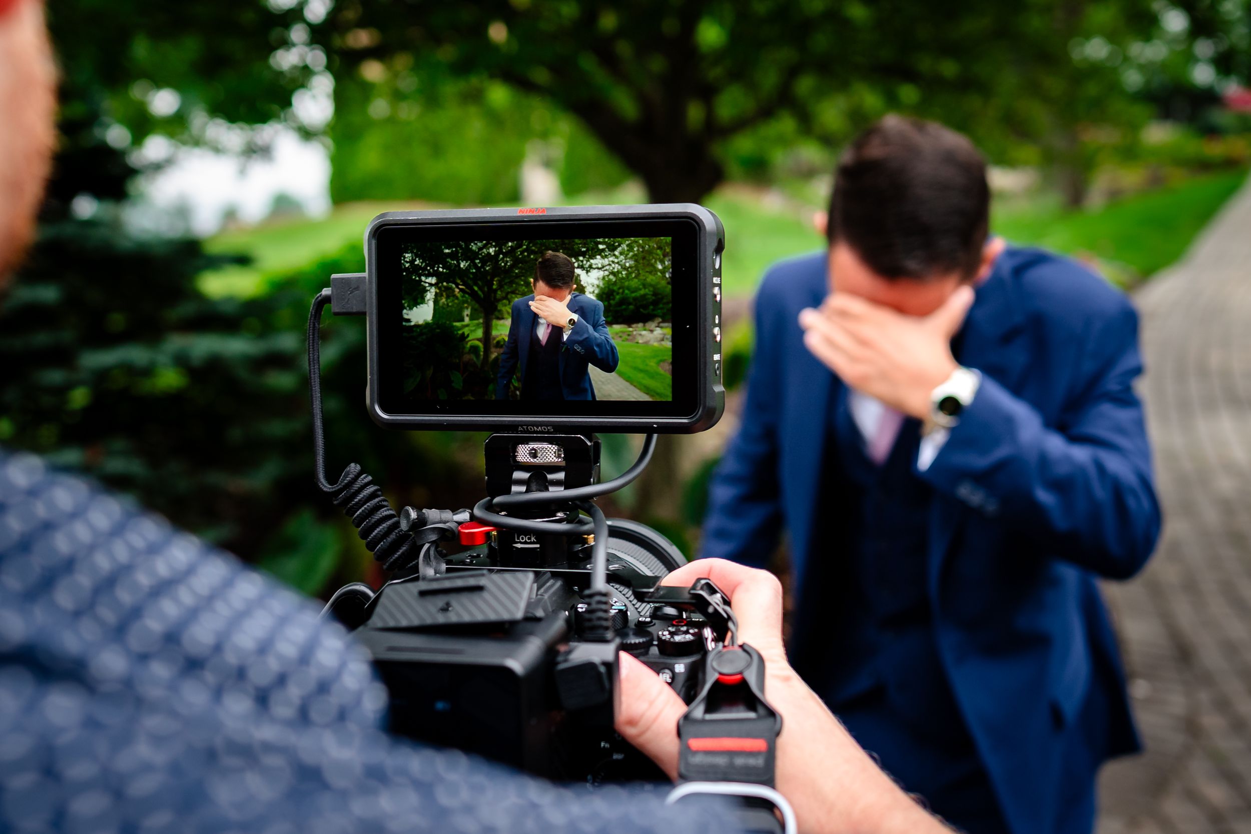 Wedding videographer filming outdoor ceremony with professional camera equipment.