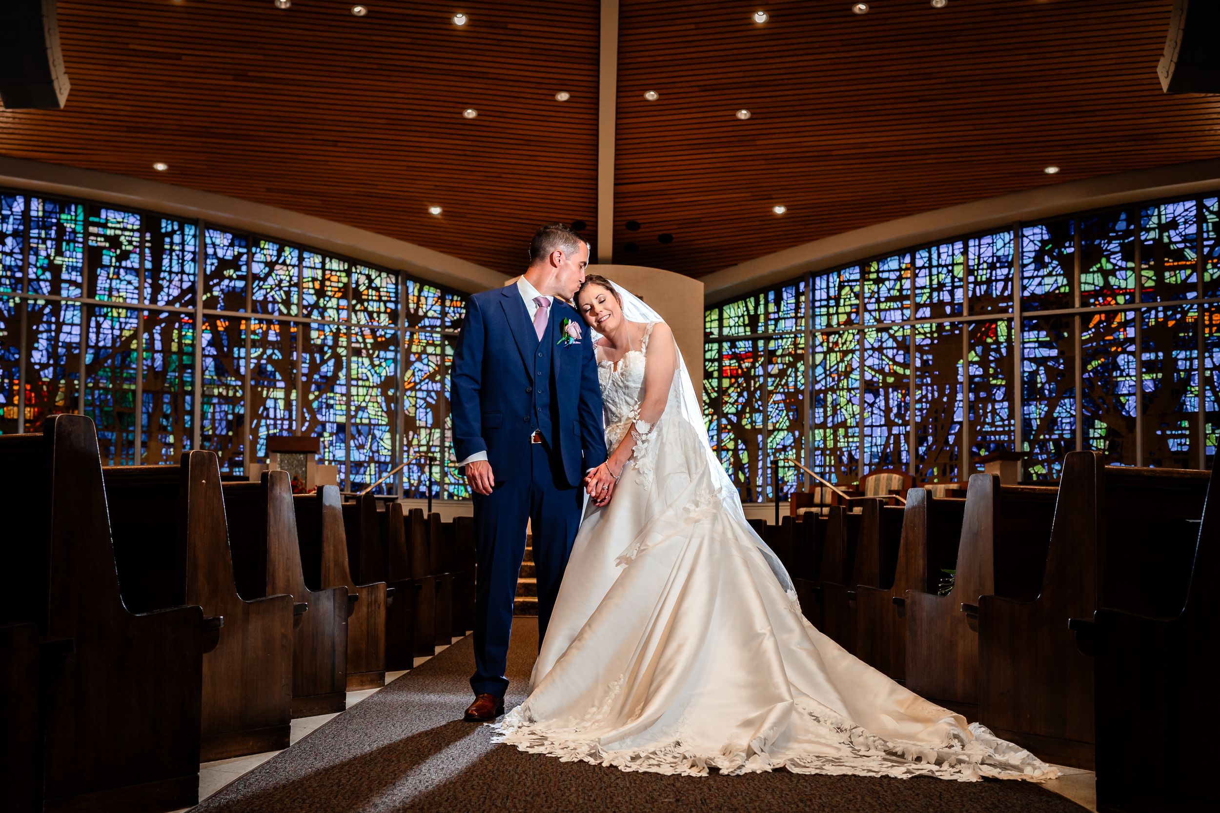 Elegant wedding ceremony setup in church with dramatic lighting and stained glass windows.