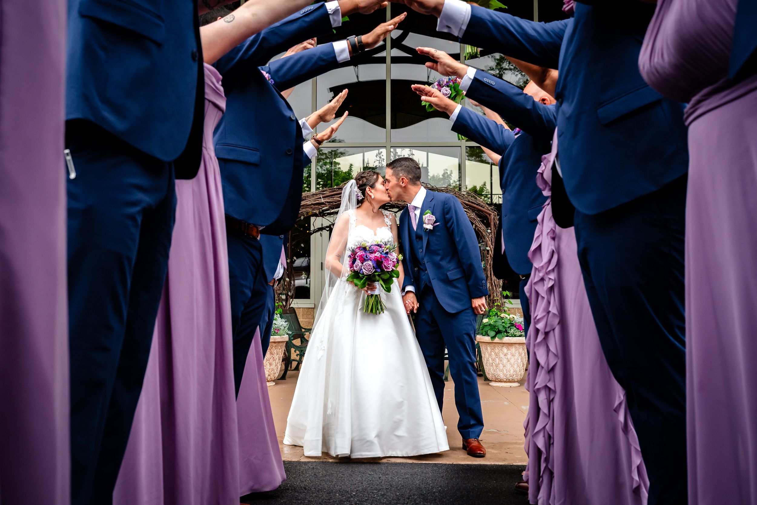 Wedding party members in navy and lavender attire gathered during outdoor ceremony.
