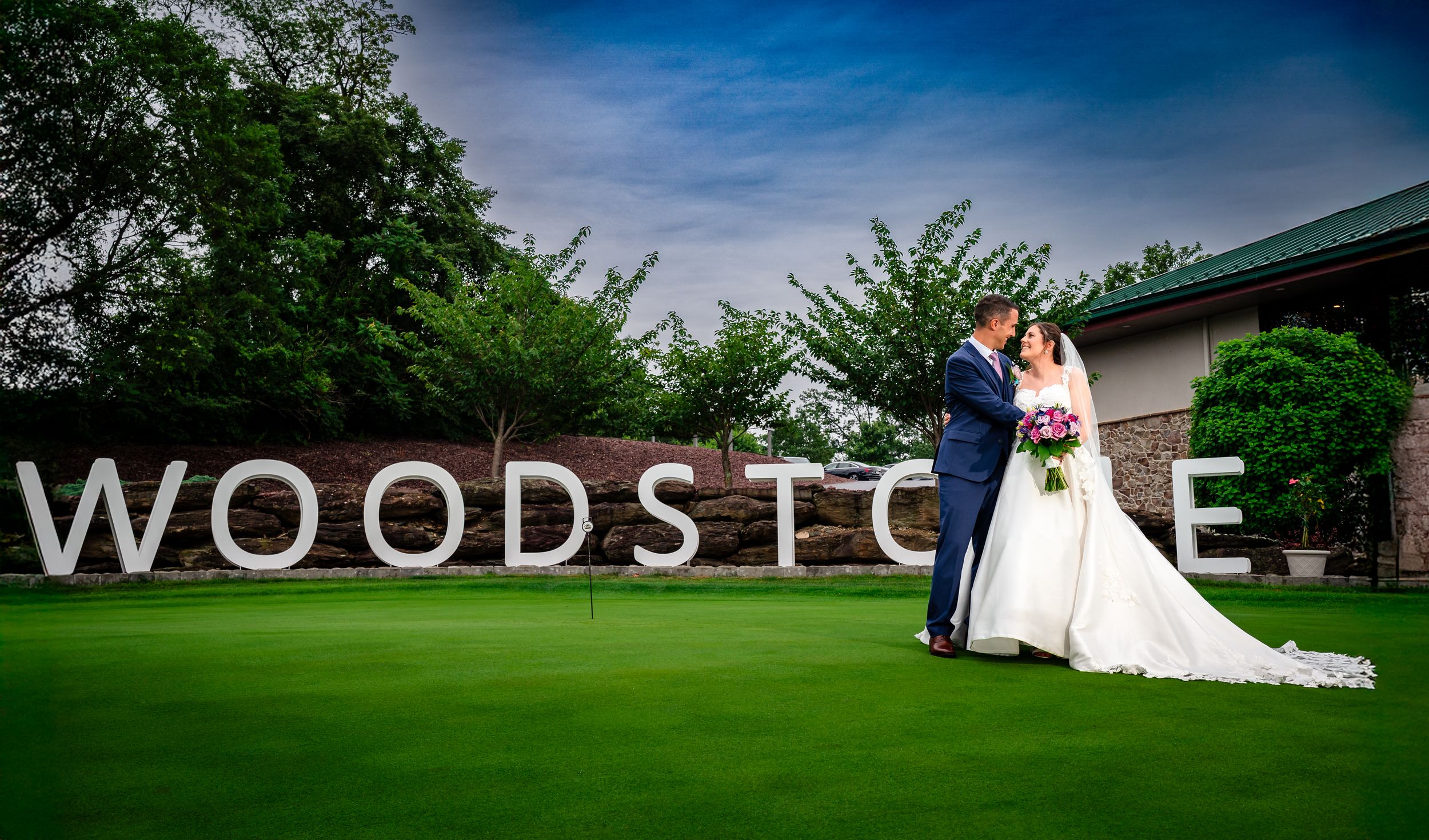 Scenic outdoor wedding venue with Woodside sign and lush green landscape.
