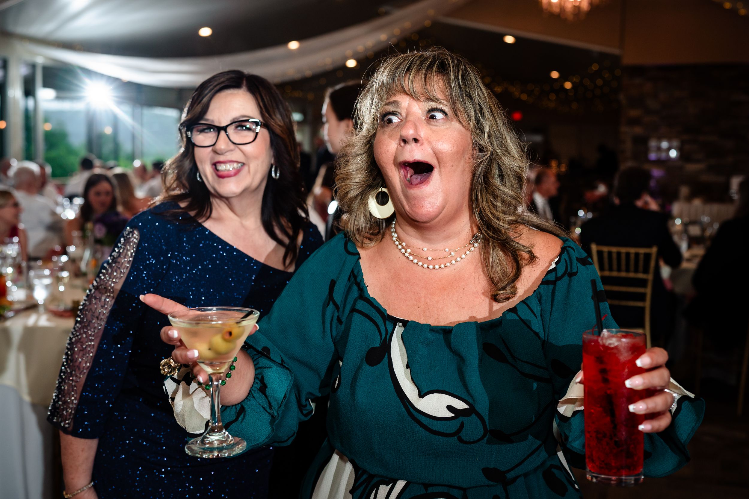 Wedding guests enjoying cocktails and laughing during reception celebration.