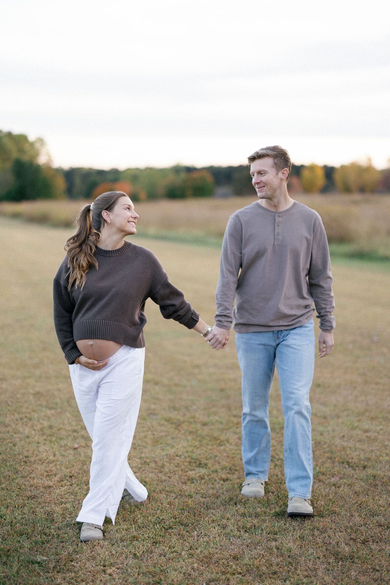 A couple shares a tender moment on a rustic dirt path surrounded by lush green foliage at sunset.