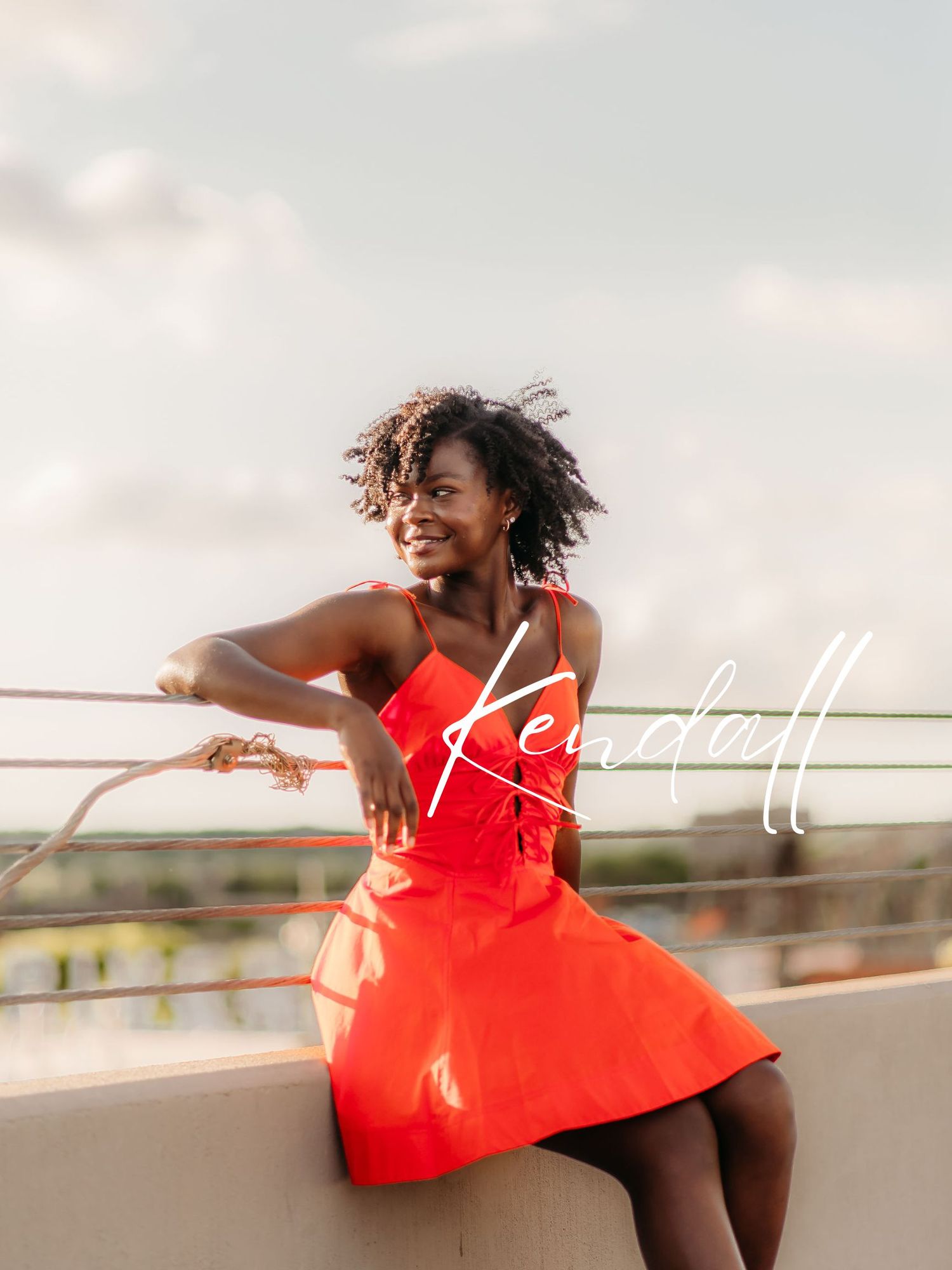 Woman in flowing red dress dances gracefully against sunset sky on rooftop.