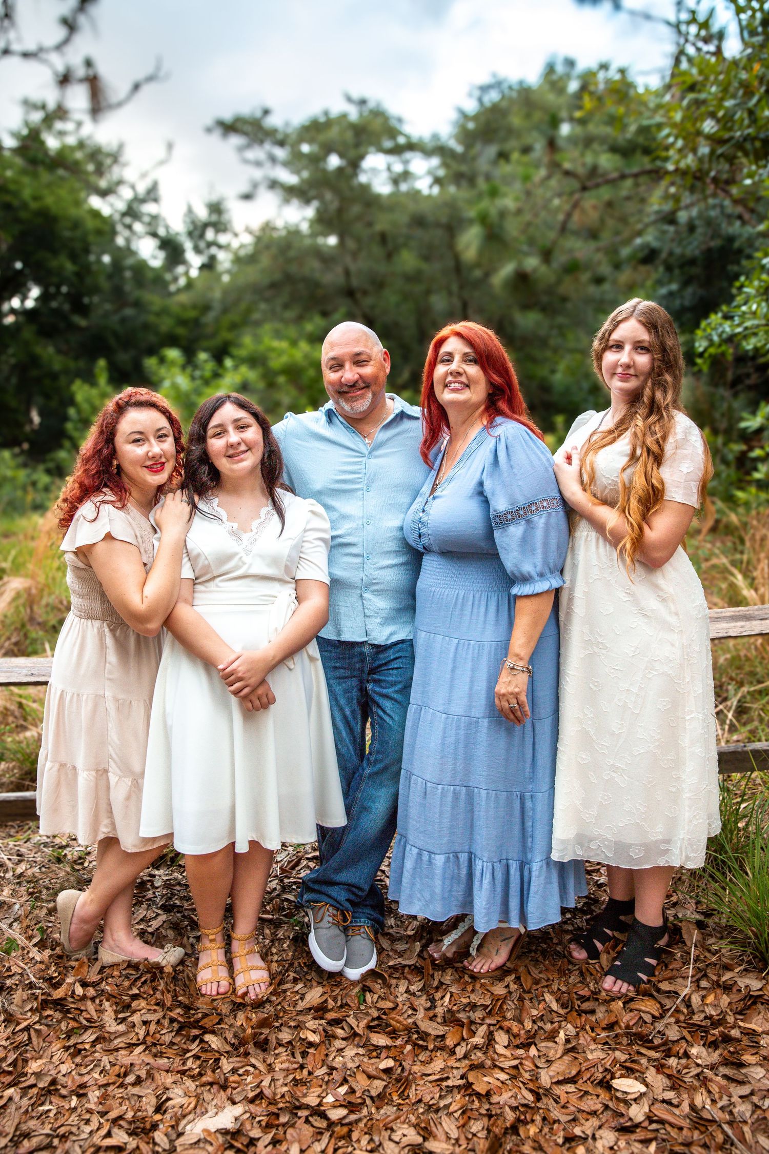 A group in coordinated blue and white outfits walk together down a wooded path while laughing and smiling.
