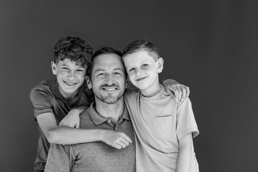 A heart-warming black and white portrait of a parent and two children sharing a joyful moment together.
