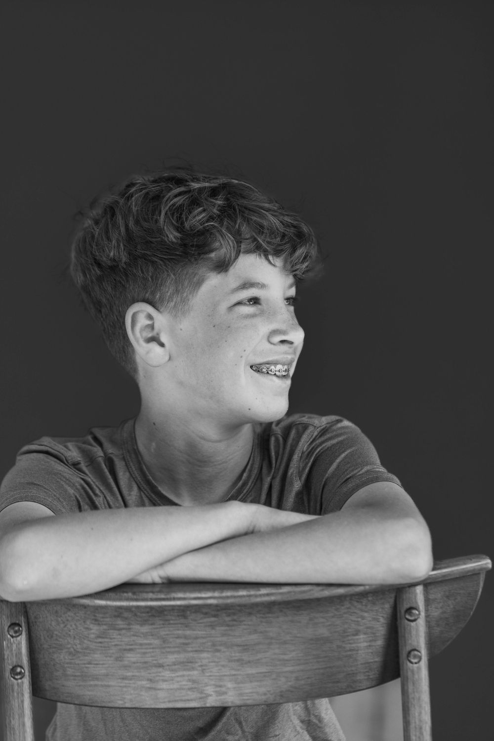 Sequence of black and white artistic portraits of someone lounging with their head resting on a wooden chair.