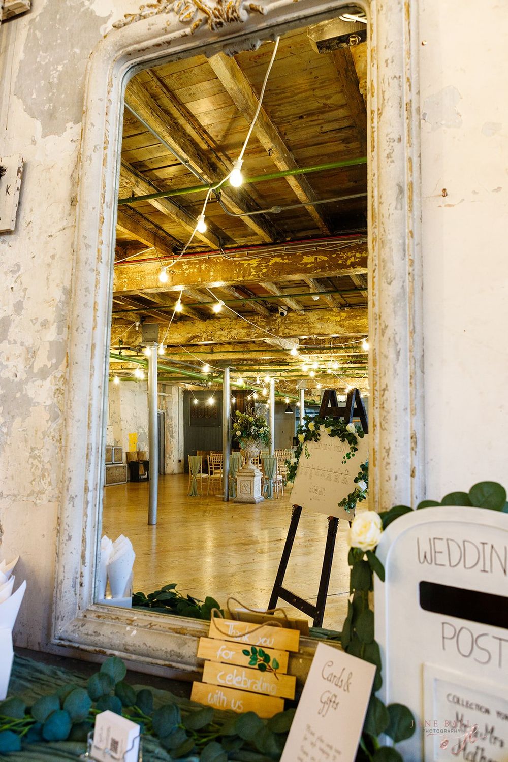 Industrial warehouse space with exposed brick walls, wooden beams, and string lights creating a rustic event venue atmosphere.