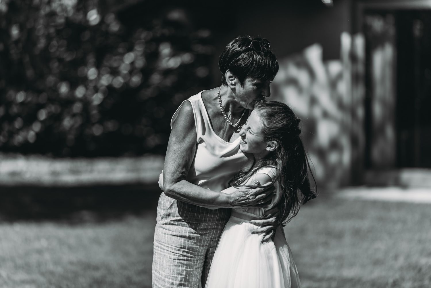 A black and white intimate moment captured between two people in an outdoor setting.