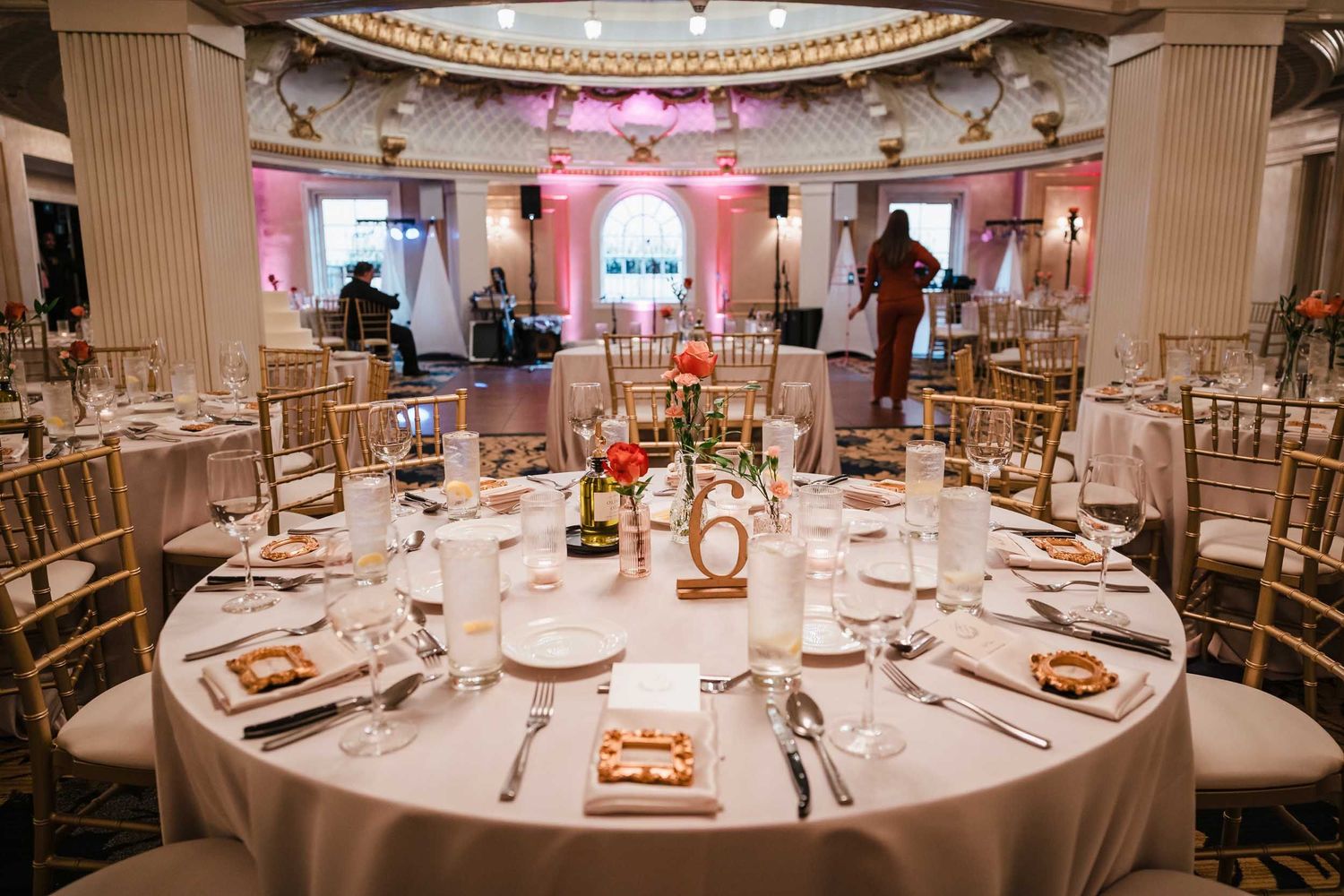 Wedding reception tables set inside the Dome Room at the Lenox Hotel in Boston with pink uplighting and floral centerpieces