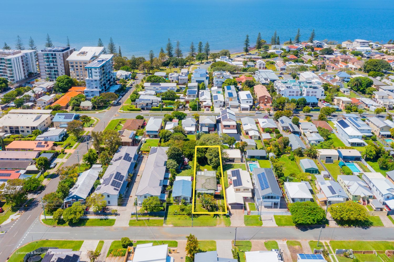 Aerial view of a beachside Australian suburb with highlighted property lot near the ocean and local amenities.