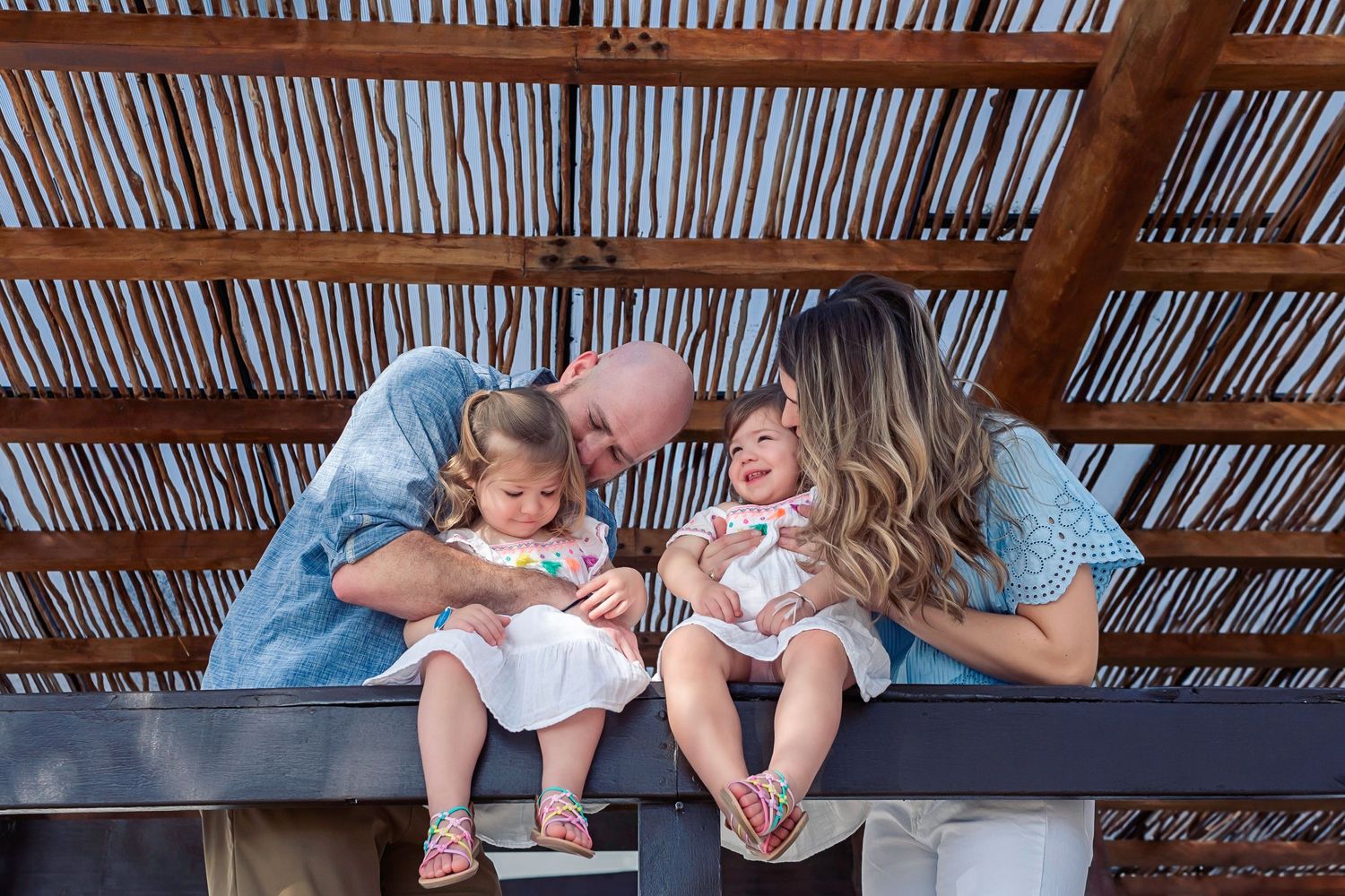 A tender family moment shared under a wooden slatted roof.