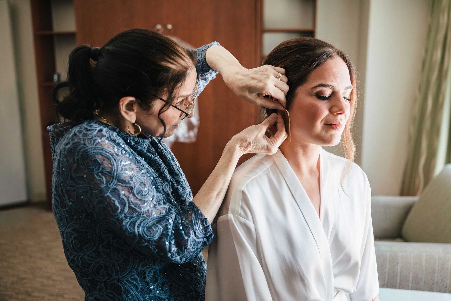 Bride getting ready with her mother helping her put on earrings before a Boston wedding ceremony