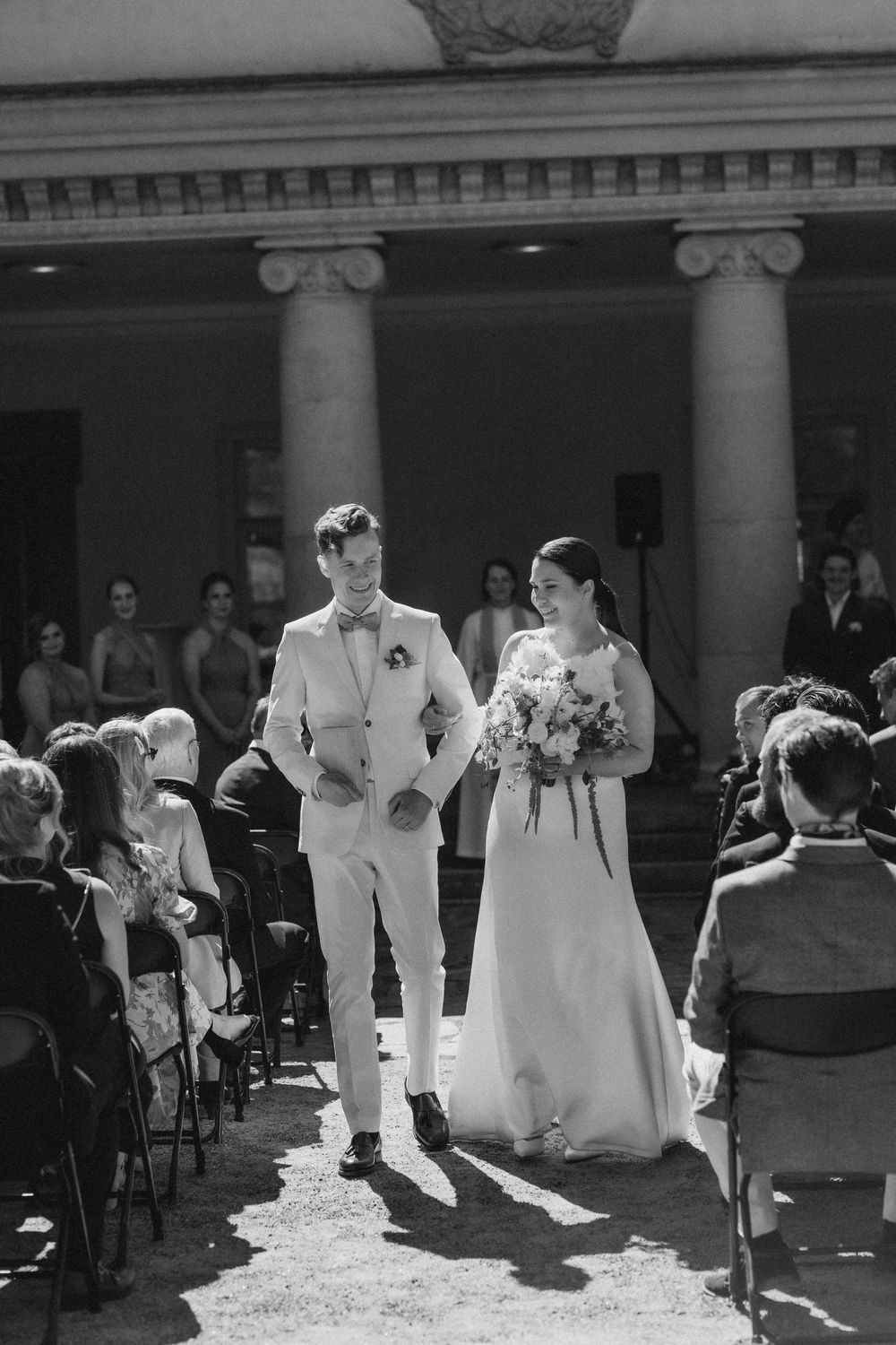 newlywed couple walking down aisle among guests outdoor wedding ceremony at Espoon Kartano documentary wedding photography Finland