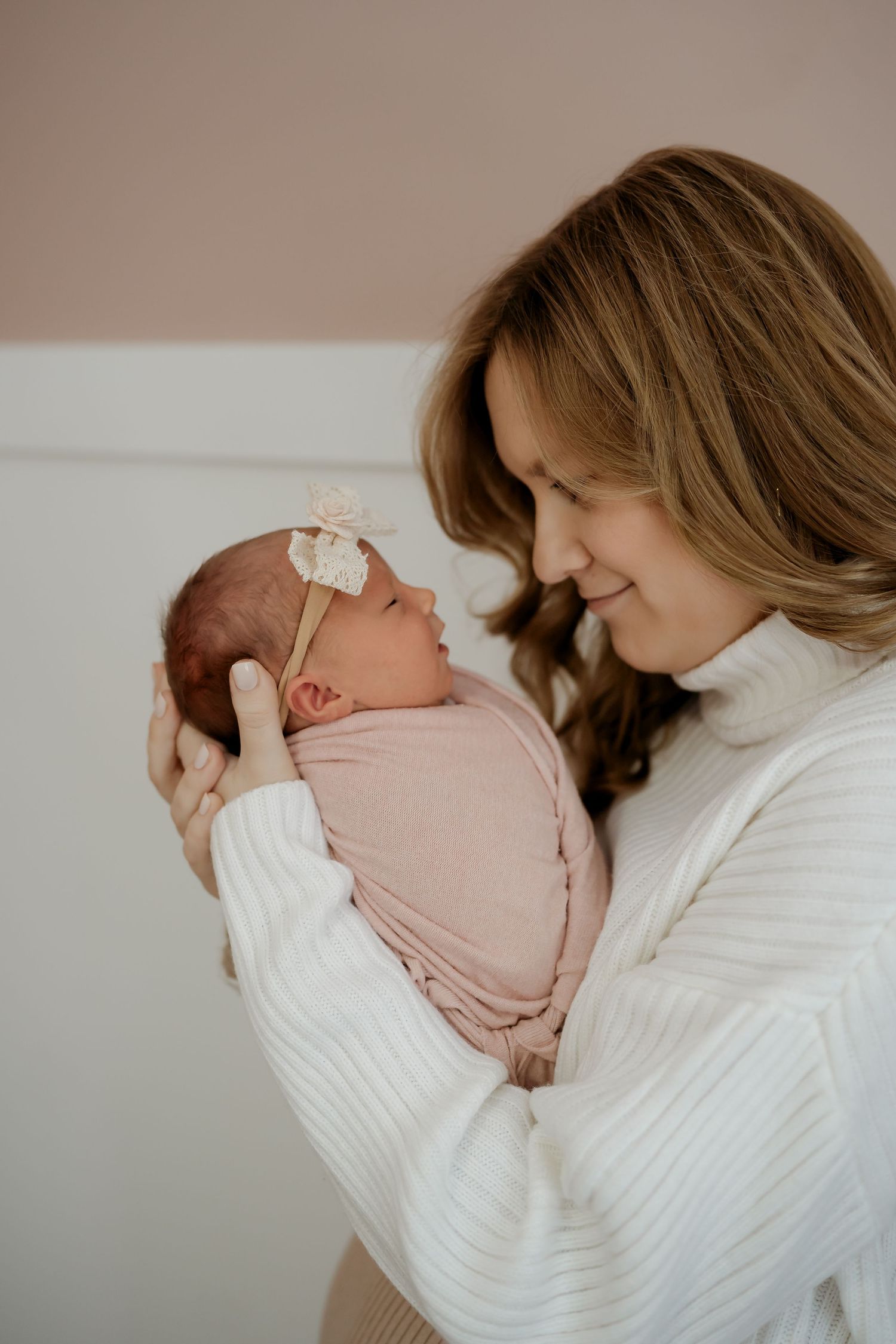 A tender moment between a parent and newborn baby wearing pink, shown in a series of intimate side profile photos.