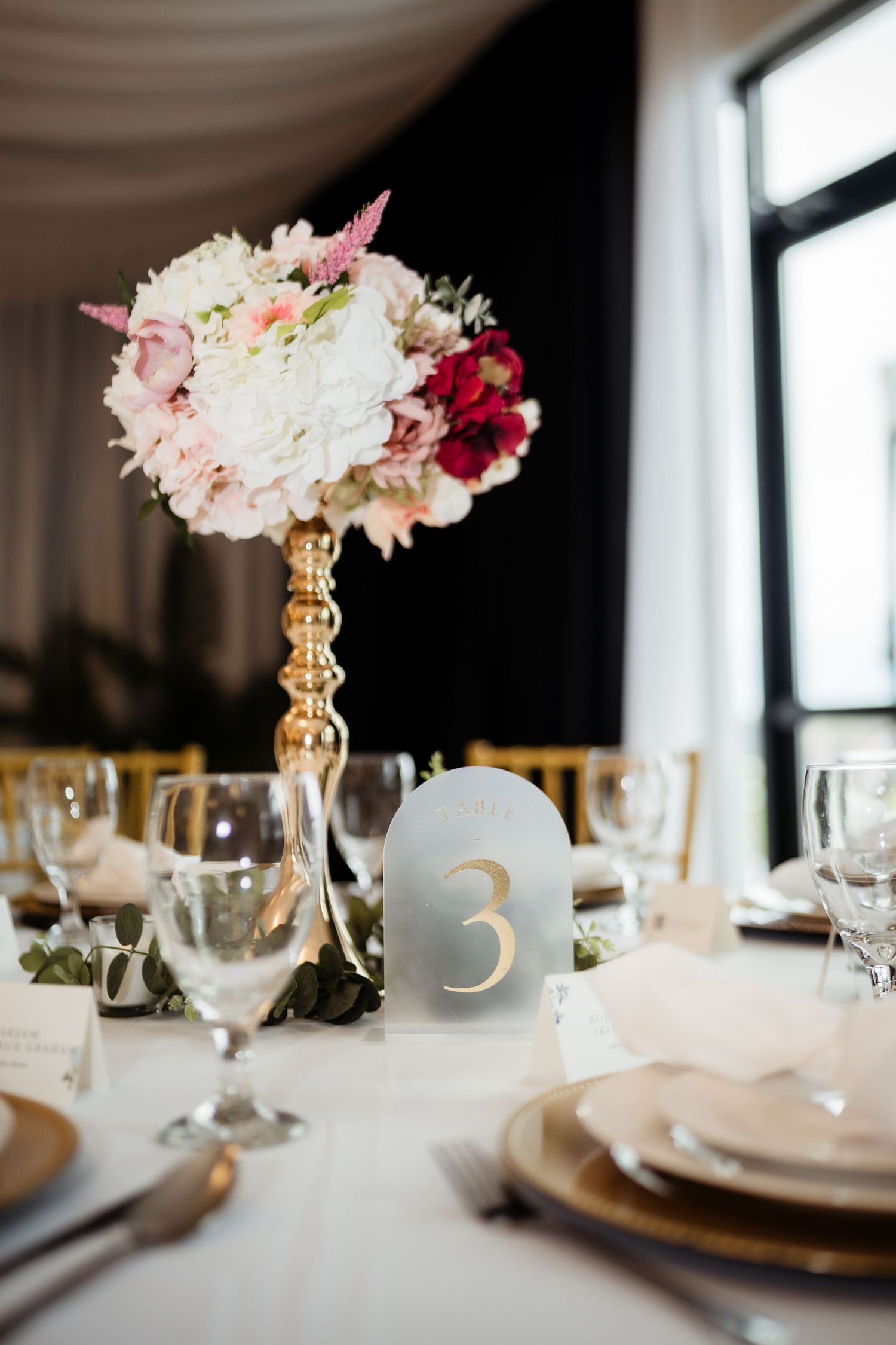 Elegant wedding reception table settings with gold candelabras and pink floral centerpieces against white linens.