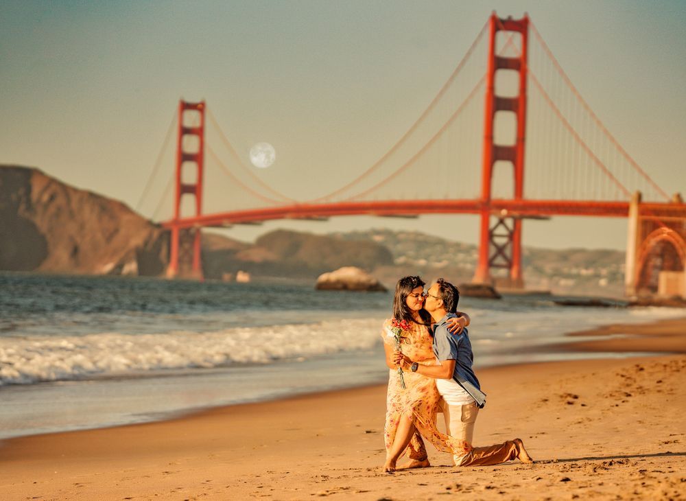 A romantic beach scene with the iconic Golden Gate Bridge in San Francisco during golden hour sunset.