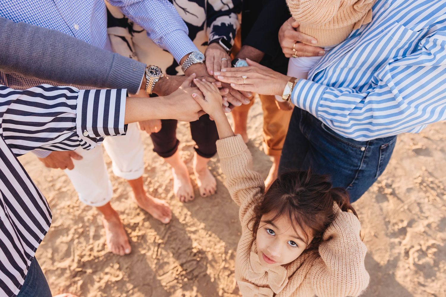 People holding sparklers and celebrating together at a beach party during sunset.