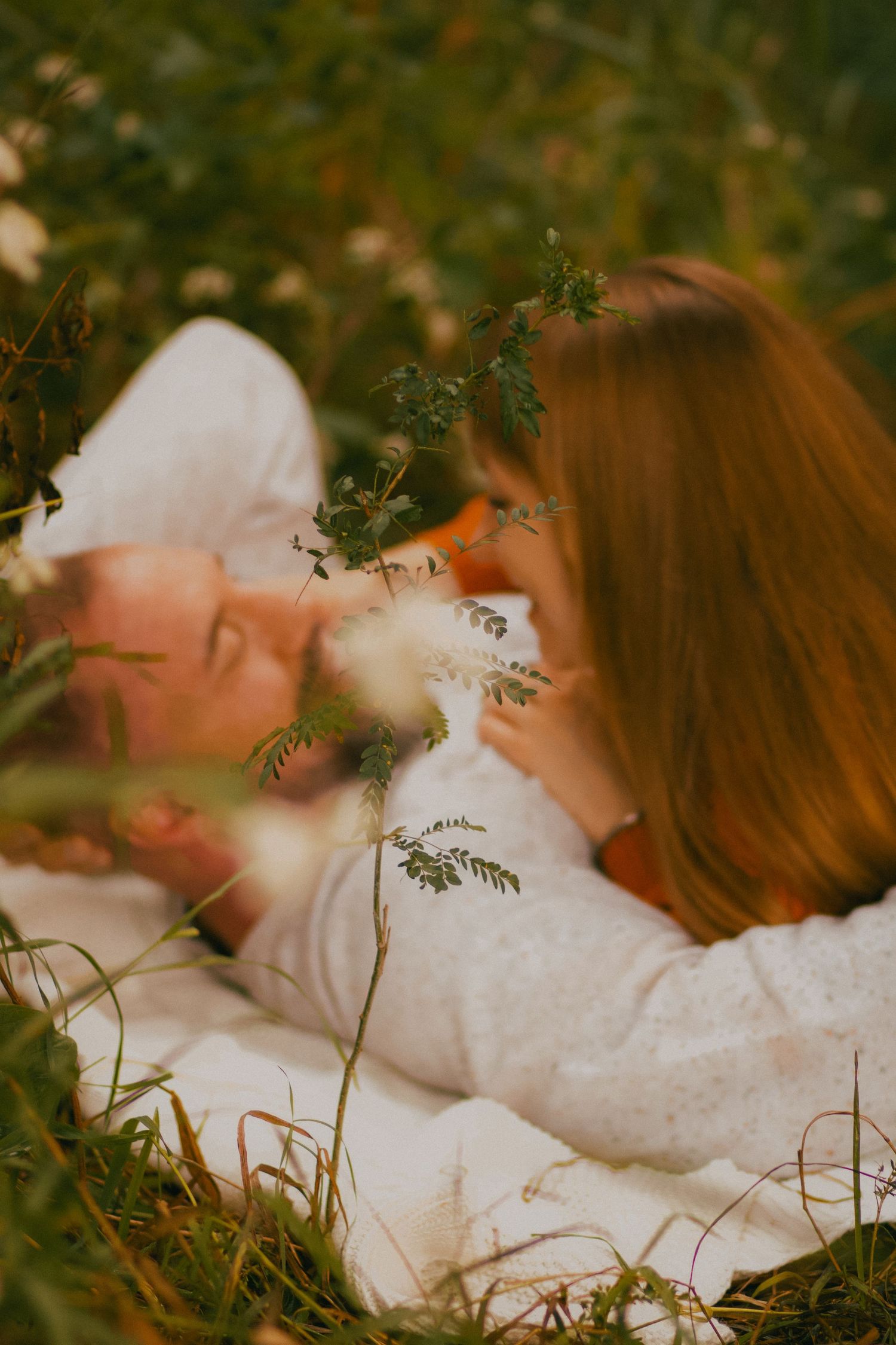 Two people embrace in a romantic pose during golden hour sunset in a rustic outdoor setting.