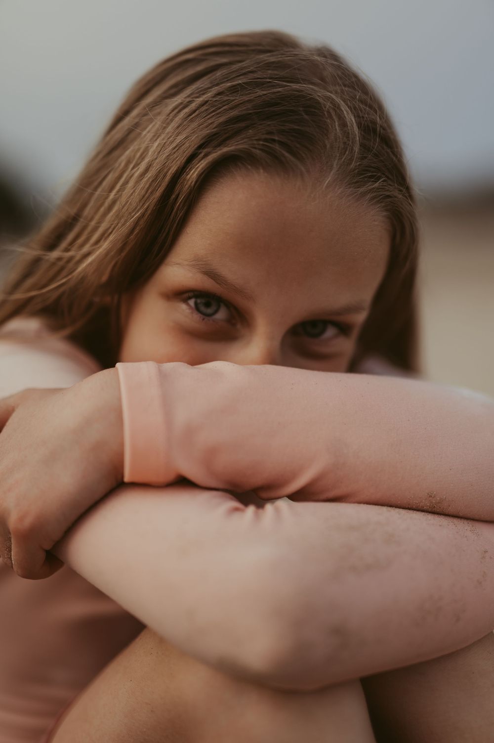Young girl with brown hair gazing at camera with a contemplative expression on Lake Michigan during a creative session in Port Washington.