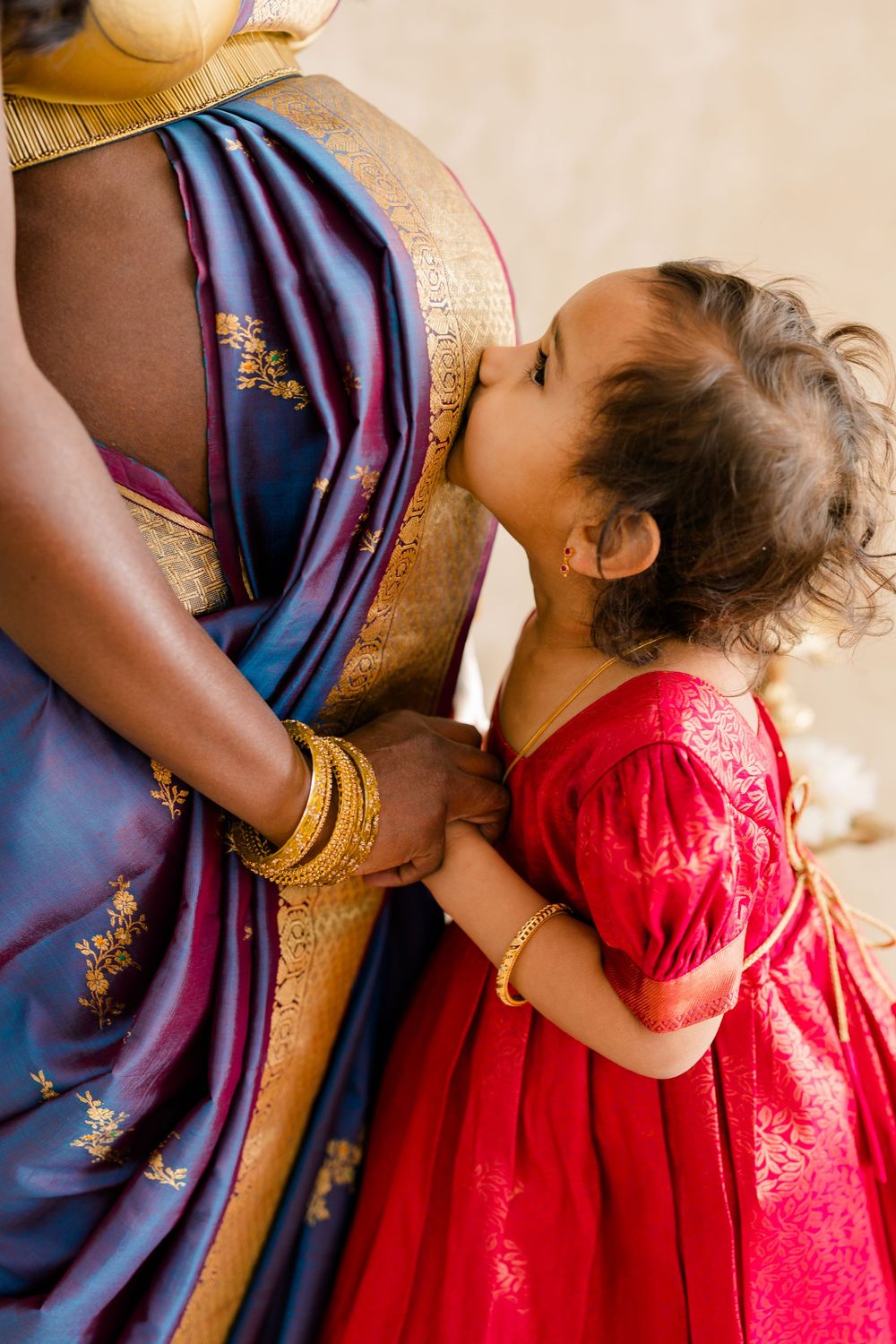 A series of tender moments showing a child in a red dress embracing someone wearing blue traditional Indian attire.