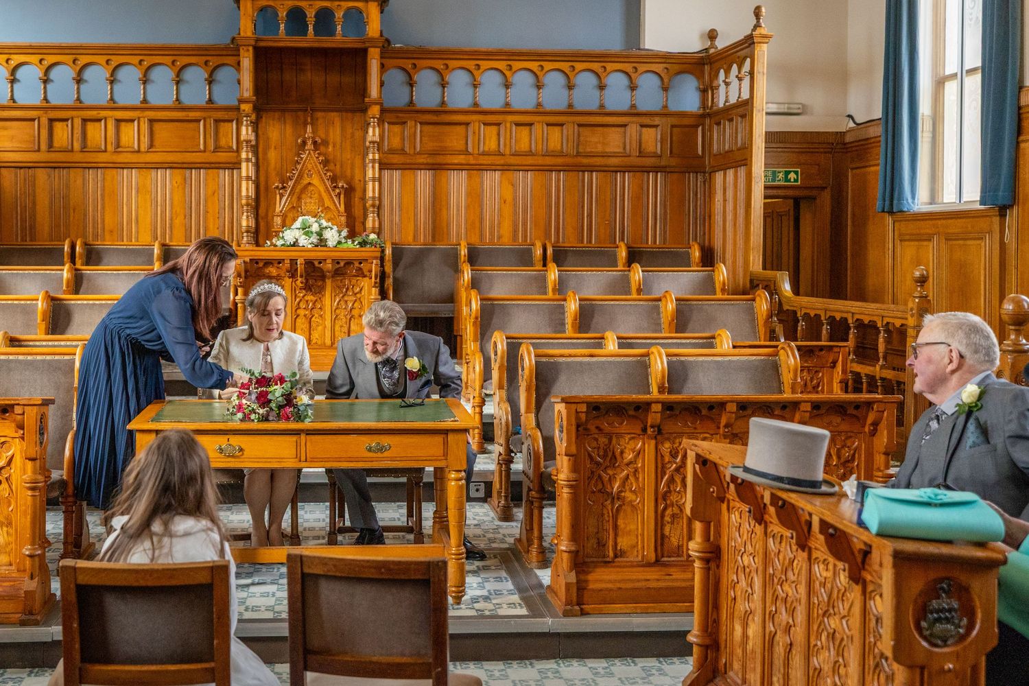 Guests seated with top hat on pew
Wedding guests watching register signing at Southport Town Hall in Lancashire, candid moment