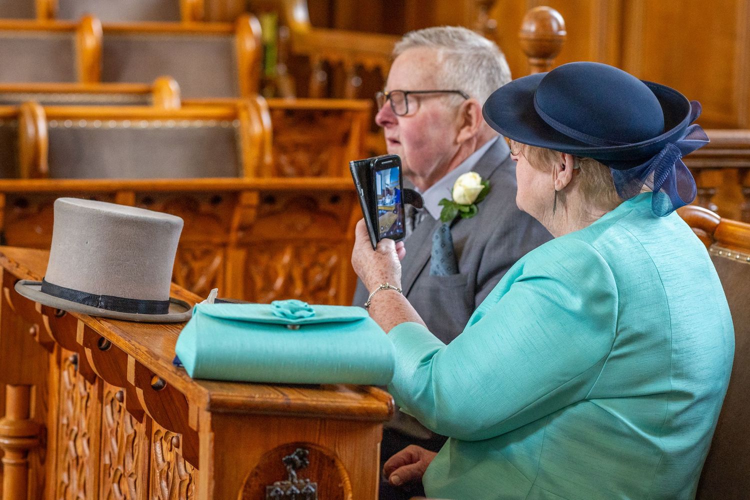 Wedding guest filming the register signing on a phone inside Southport Town Hall ceremony room.