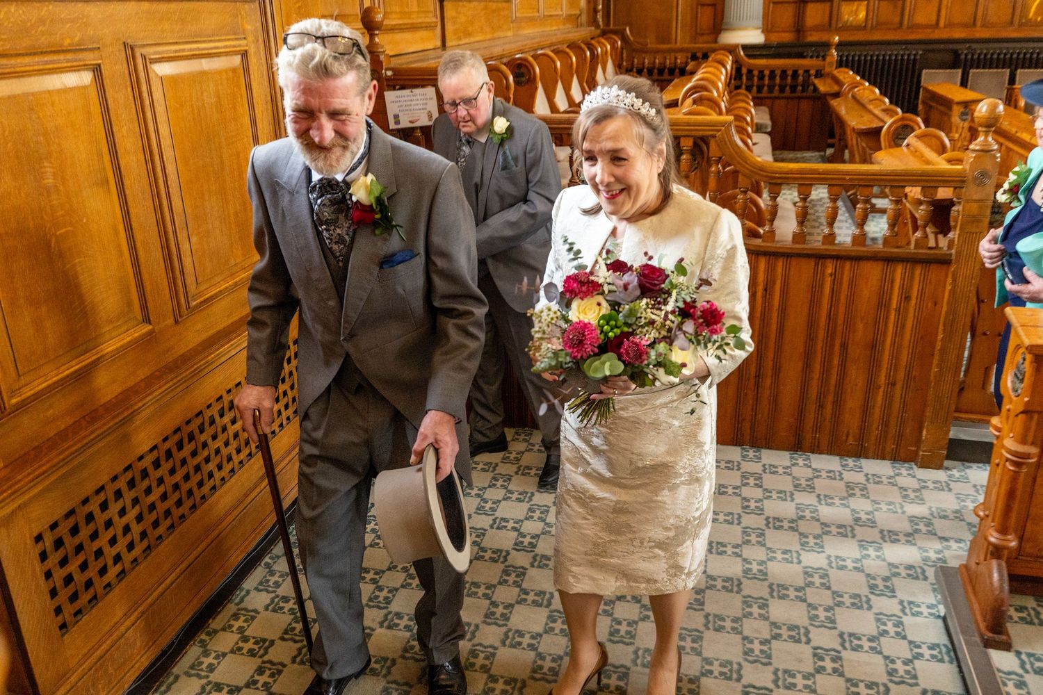 Bride and groom walk out of Southport Town Hall ceremony room smiling after signing the register, documentary wedding photography