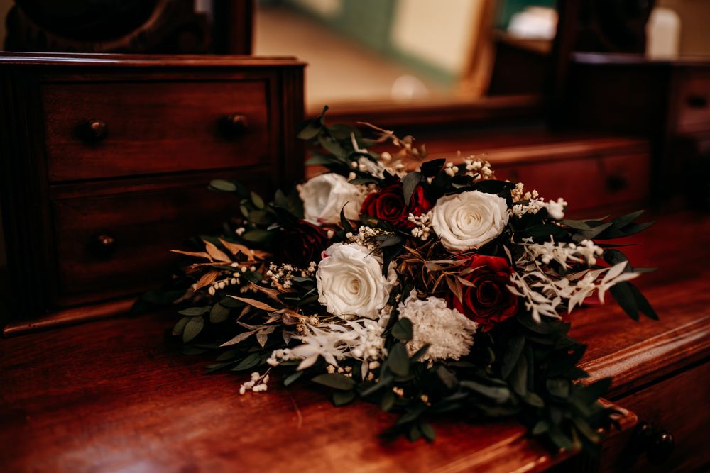 A series of elegant floral arrangements with white roses and greenery decorating a dark wooden surface.