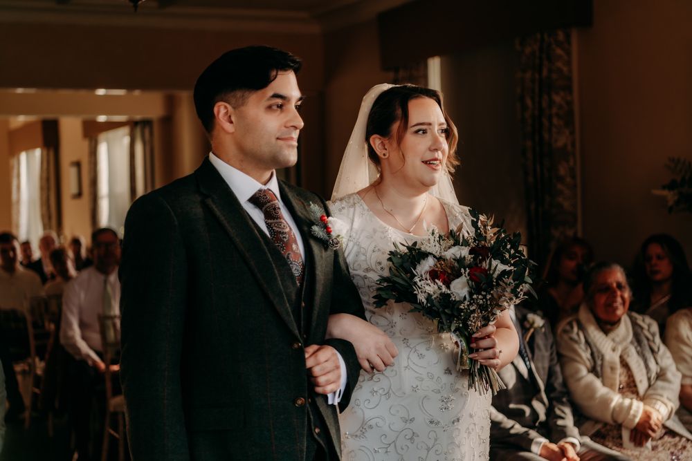 A bride and groom share intimate moments during their wedding ceremony in an elegant indoor venue.