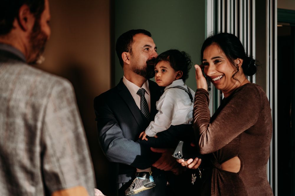 Group of wedding guests sharing candid moments and laughter in a dimly lit reception venue.