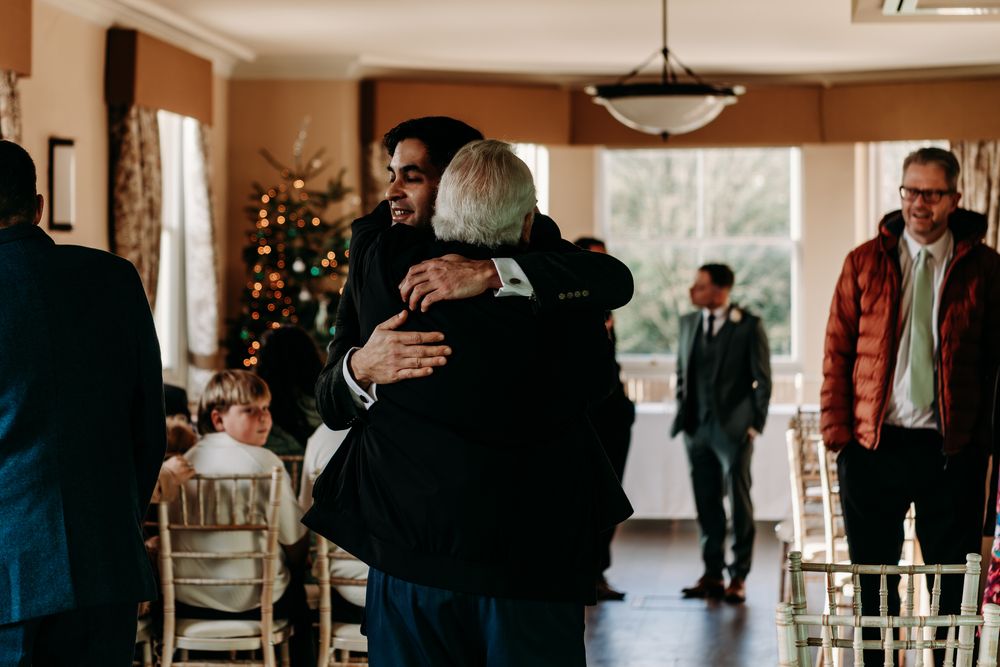 Romantic couple shares a dance at an elegant indoor wedding reception venue with guests watching in the background.