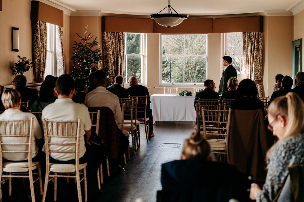 Wide angle view of an elegant wedding reception room with chiavari chairs and large windows.