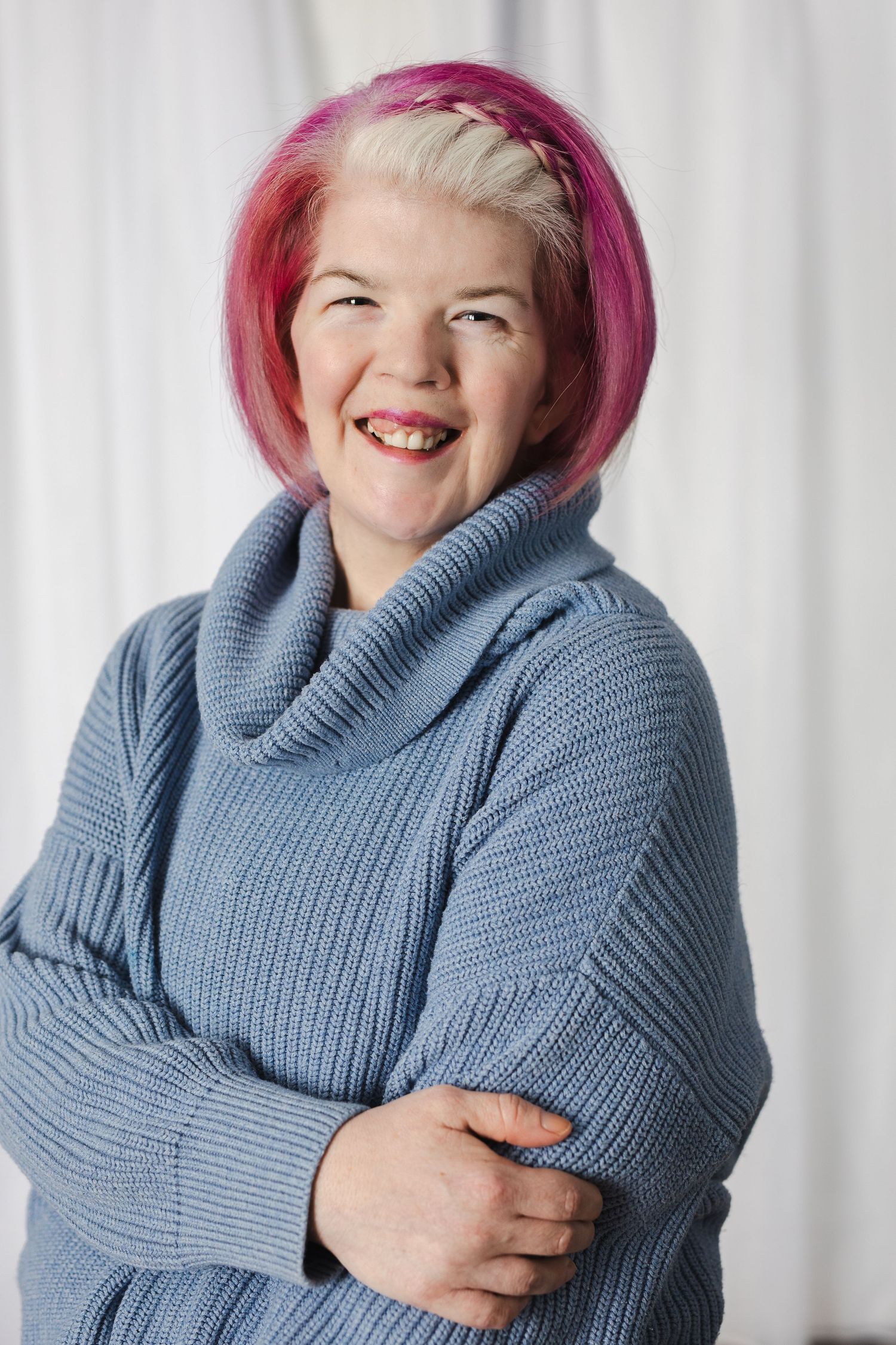 Someone wearing a cozy blue knit turtleneck sweater smiles and hugs themselves in a series of expressive poses.
