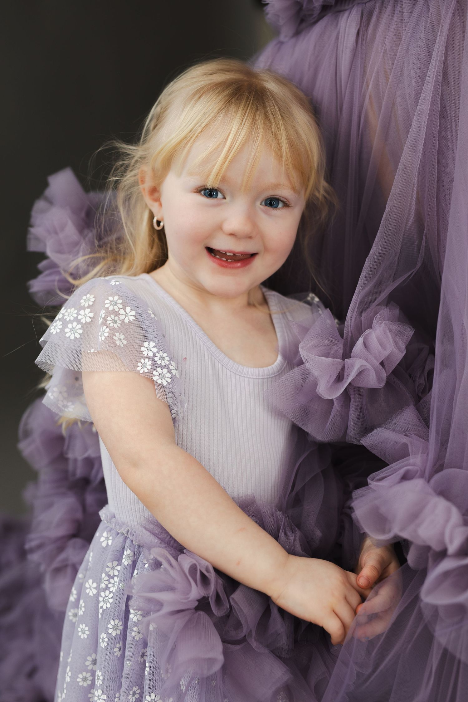 A child wearing a lavender tulle dress with floral embroidery poses in a series of playful shots.