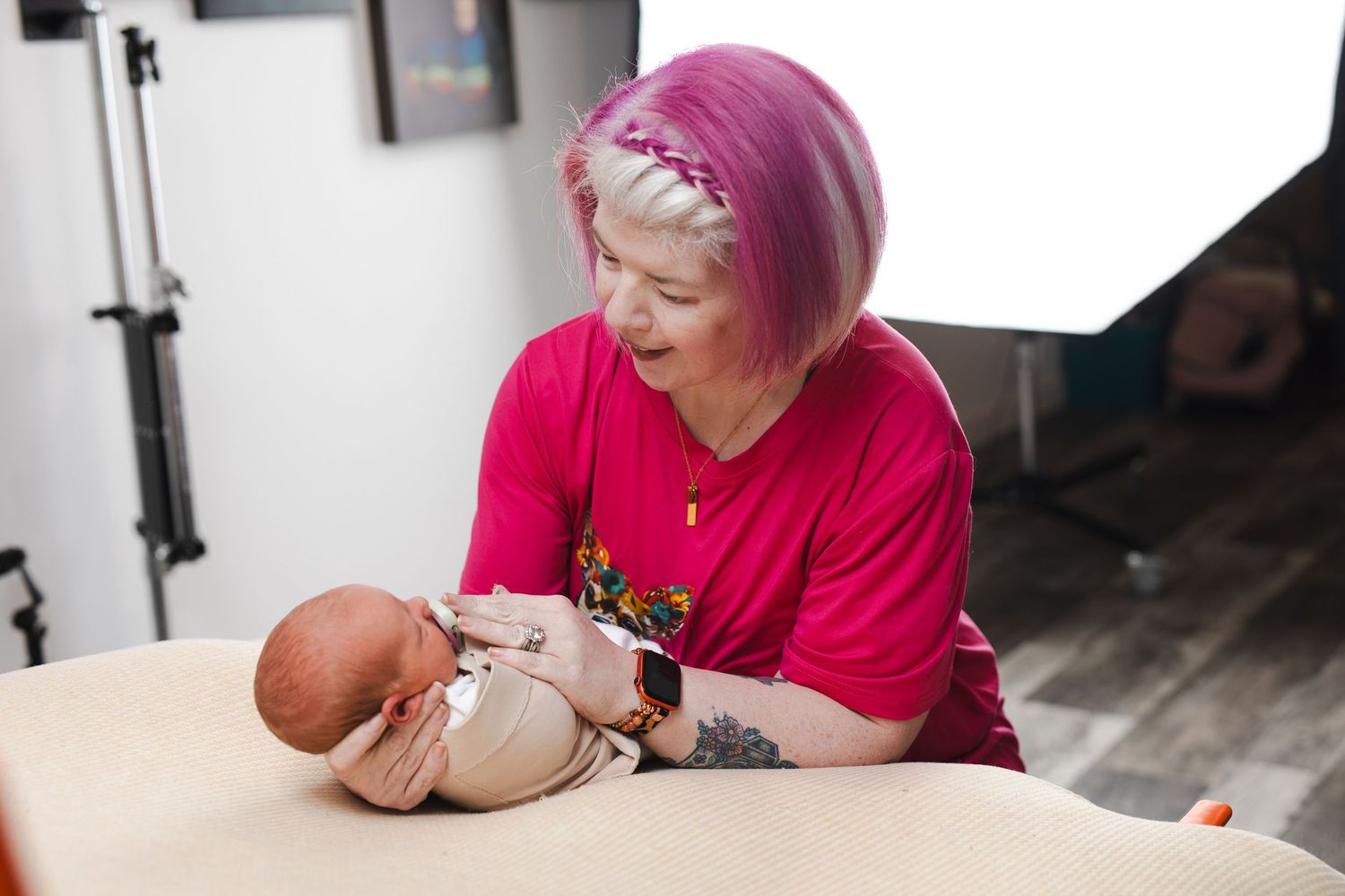 A person with pink hair demonstrates a medical procedure on a training mannequin in a healthcare setting.