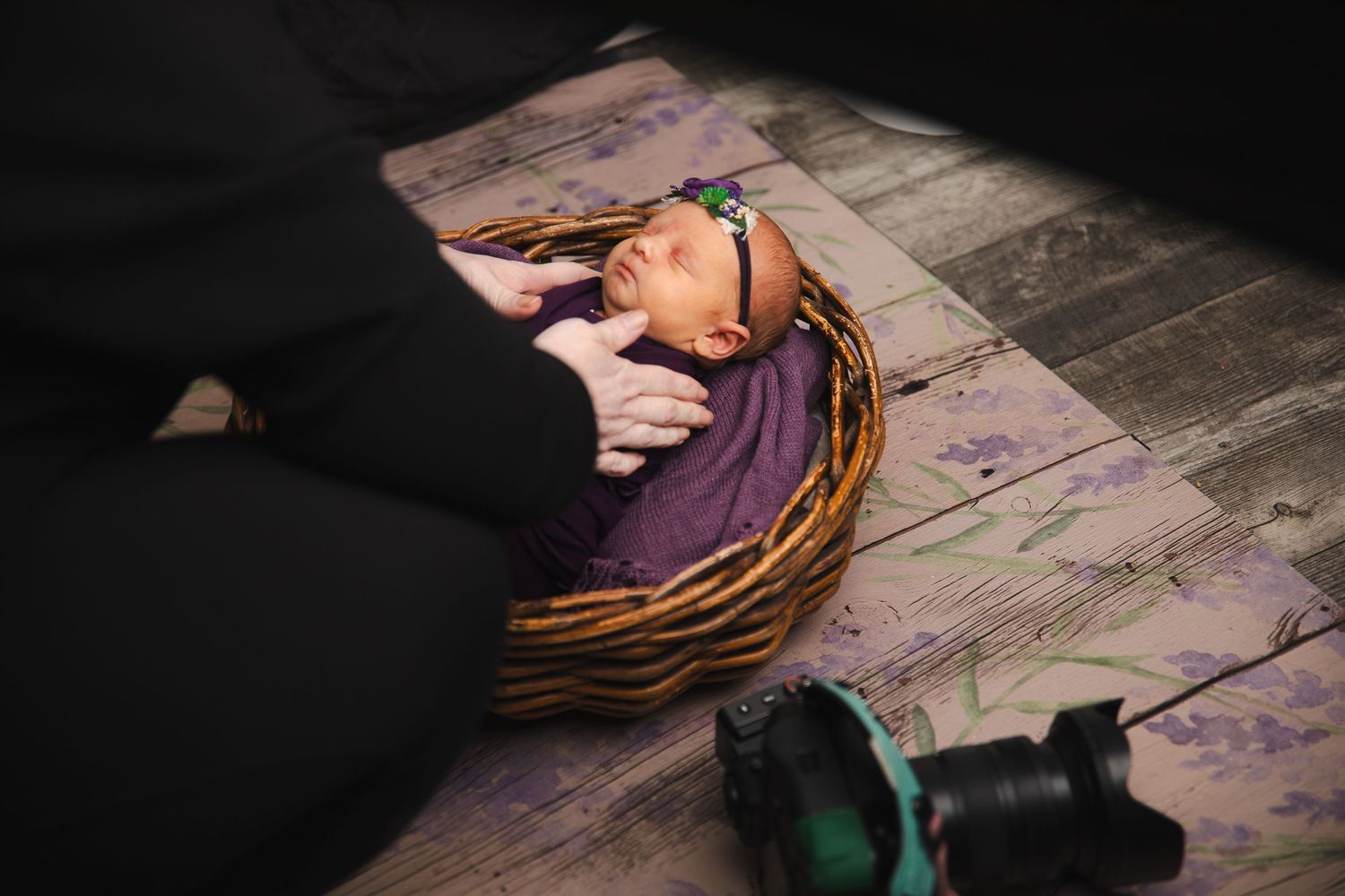 A person's hands work on a colorful craft project using yarn and string on a rustic wooden surface.