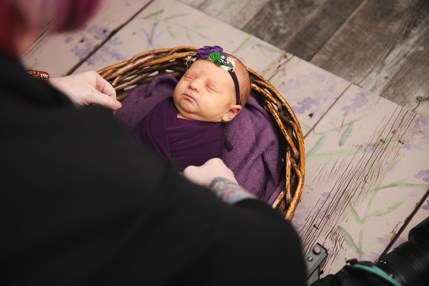 Person with pink hair and dreadlocks resting on rustic wooden flooring in dark attire.