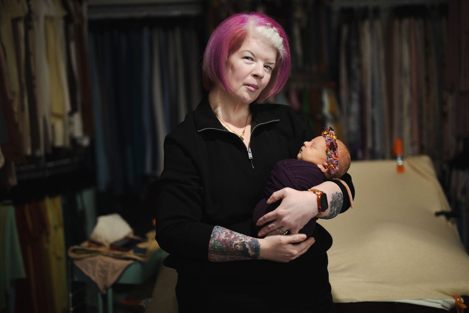 A person with pink hair holds and examines a brown egg in a dimly lit room.