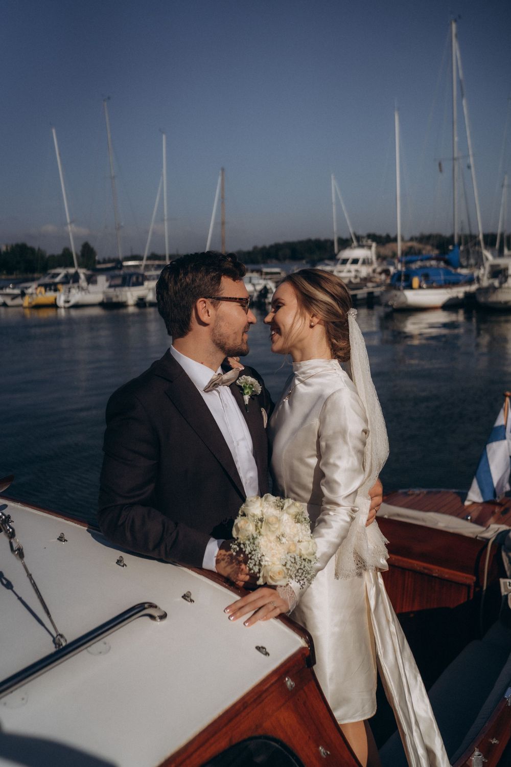 Hääpari suutelemassa veneessä Helsingin merimaisemassa