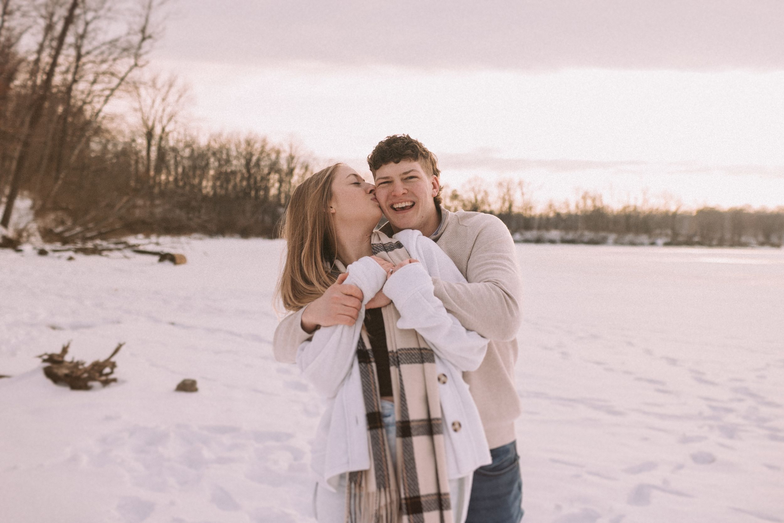 Couple sharing a romantic moment in a snowy winter landscape with a thermos flask.
