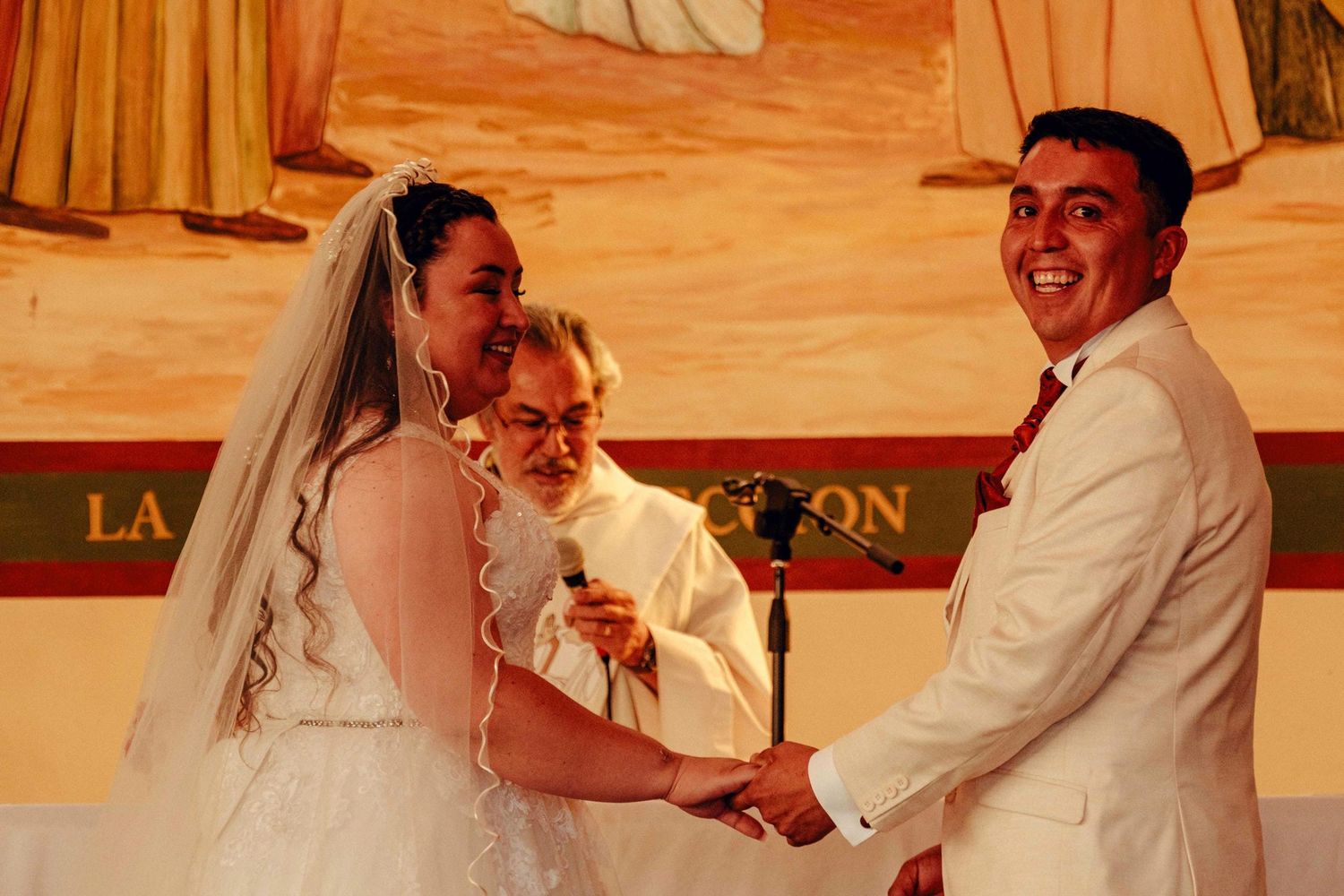 Pareja de novios compartiendo momento de alegría en recepción de matrimonio en lugar cálido interior.