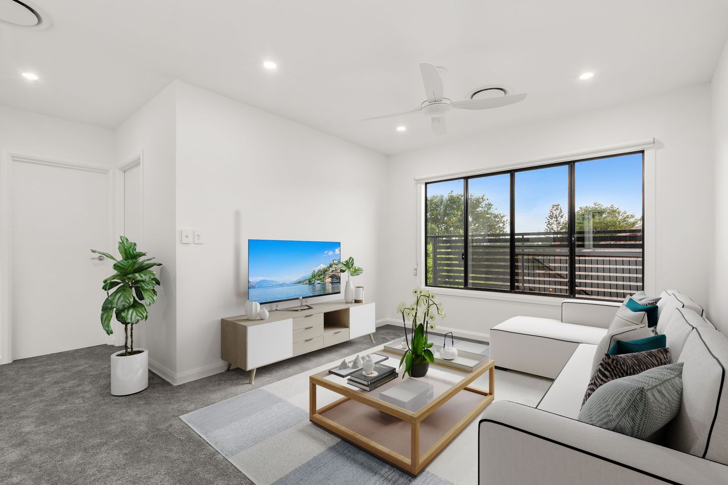 Modern living room with white sectional sofa, ceiling fan, large window, and light grey tiled floors.