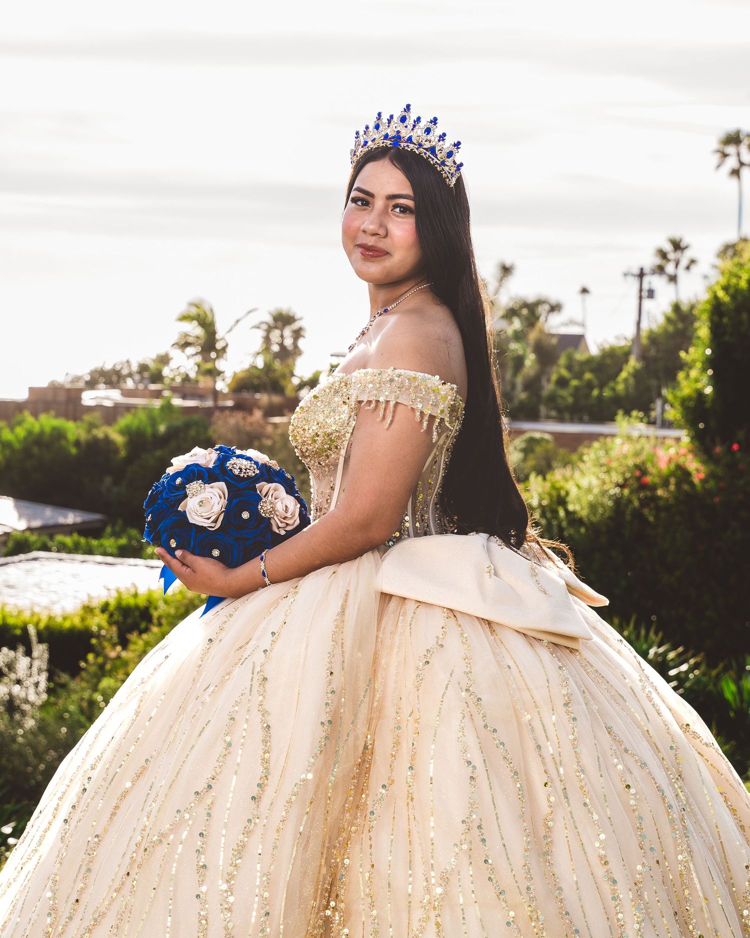 A quinceañera celebration featuring an elegant champagne-colored ball gown with intricate beading and a full tulle skirt.